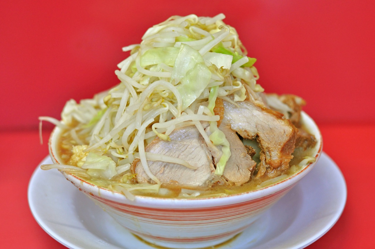 A massive bowl of Jiro-inspired ramen piled with garlic, bean sprouts, and fatty pork